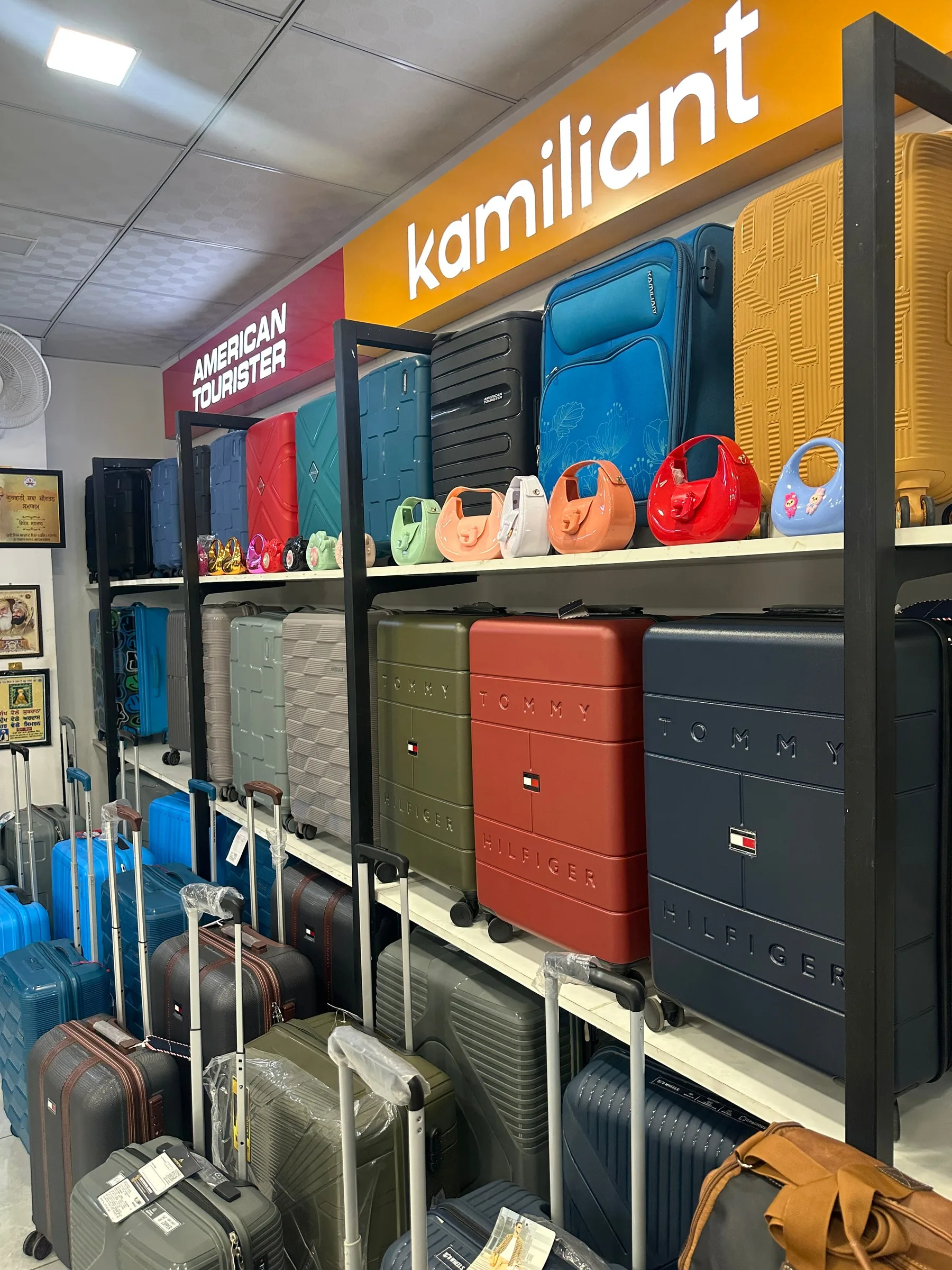 American Tourister and Kamiliant signs above the luggage on display at Rama Bags.
